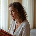 A thoughtful woman, Maria, sketching in a notebook, suggesting creative problem-solving and focus.